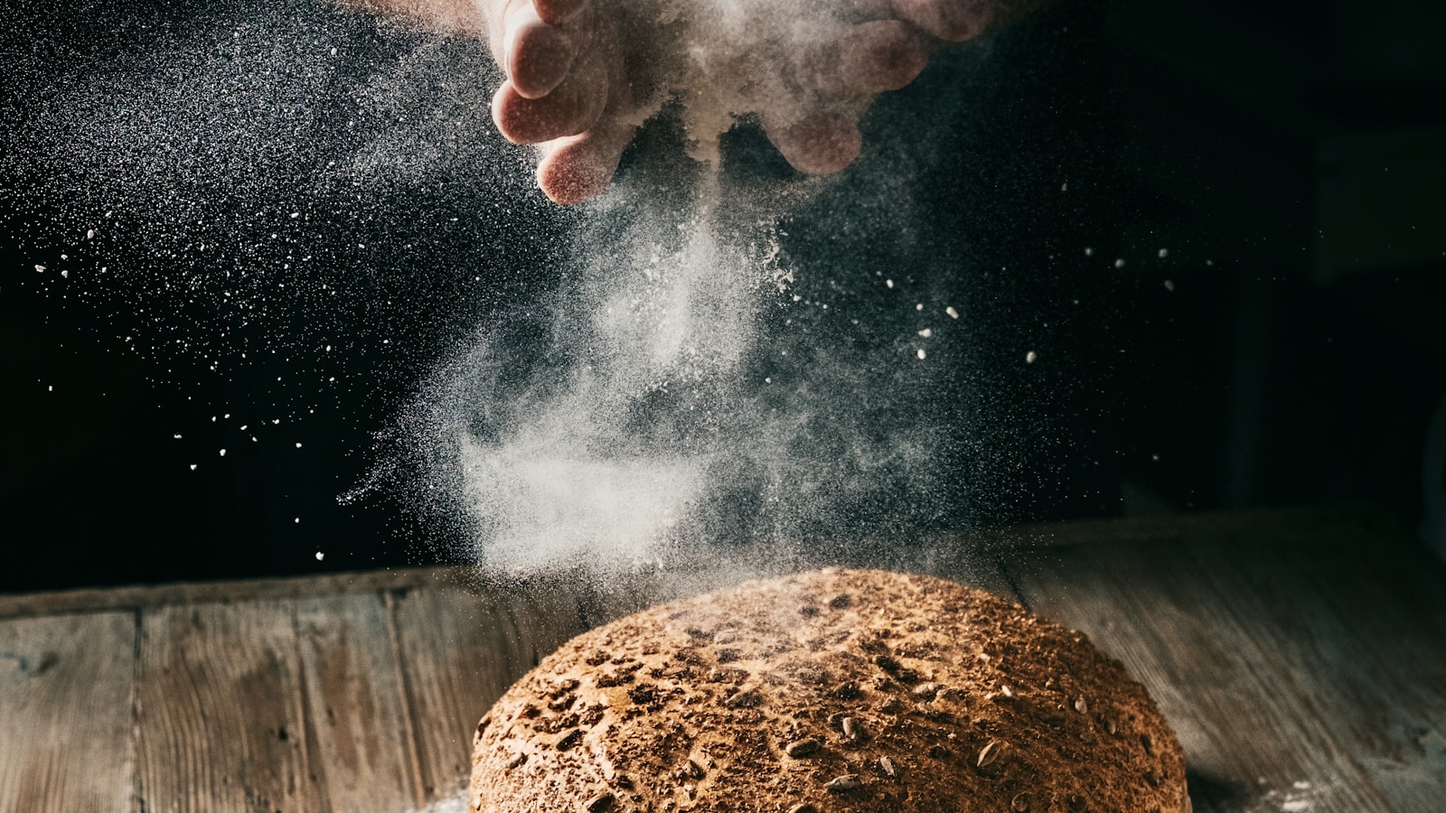 Bread loaf being dusted with flour — the raw material